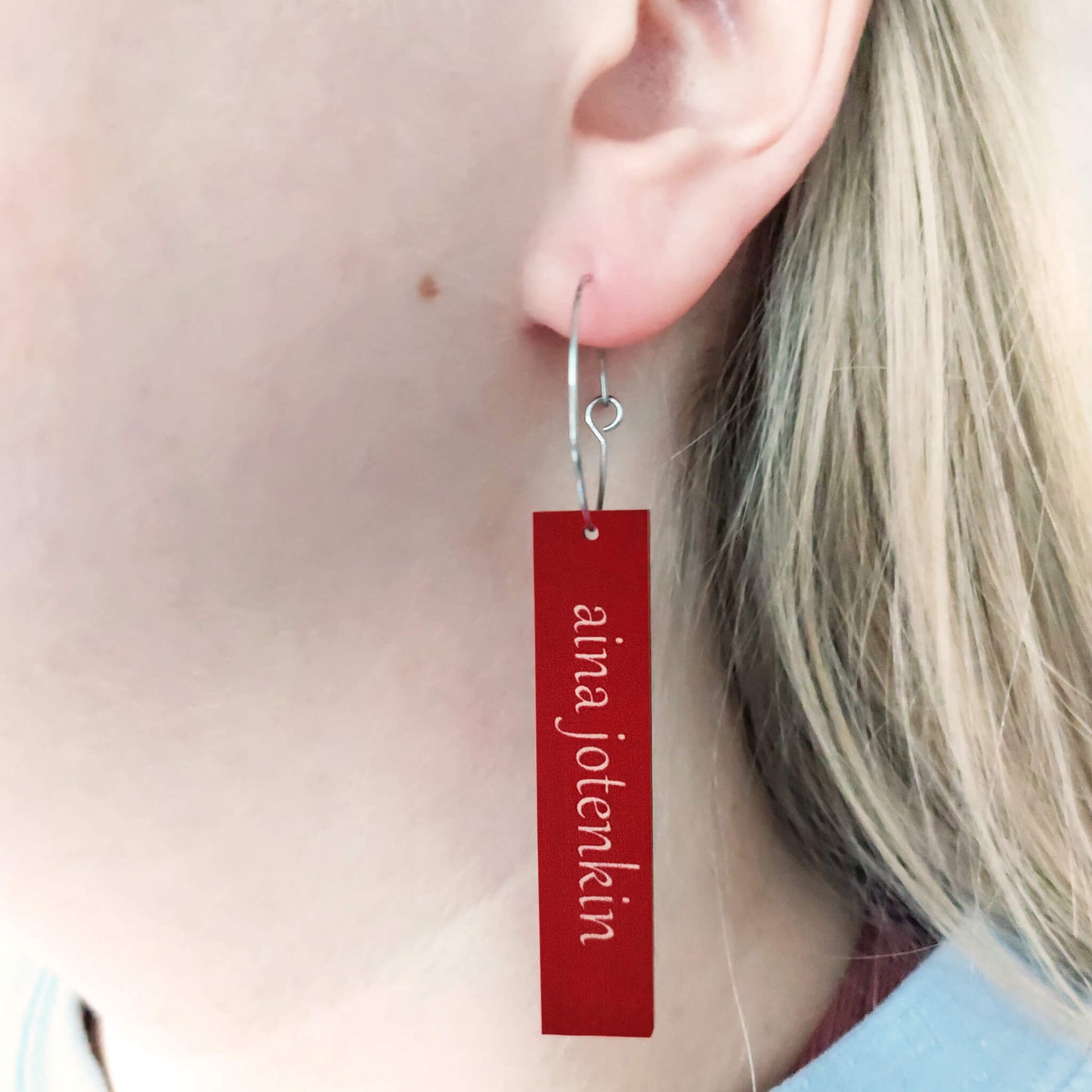 Puinen korvakoru, jossa teksti "aina jotenkin".