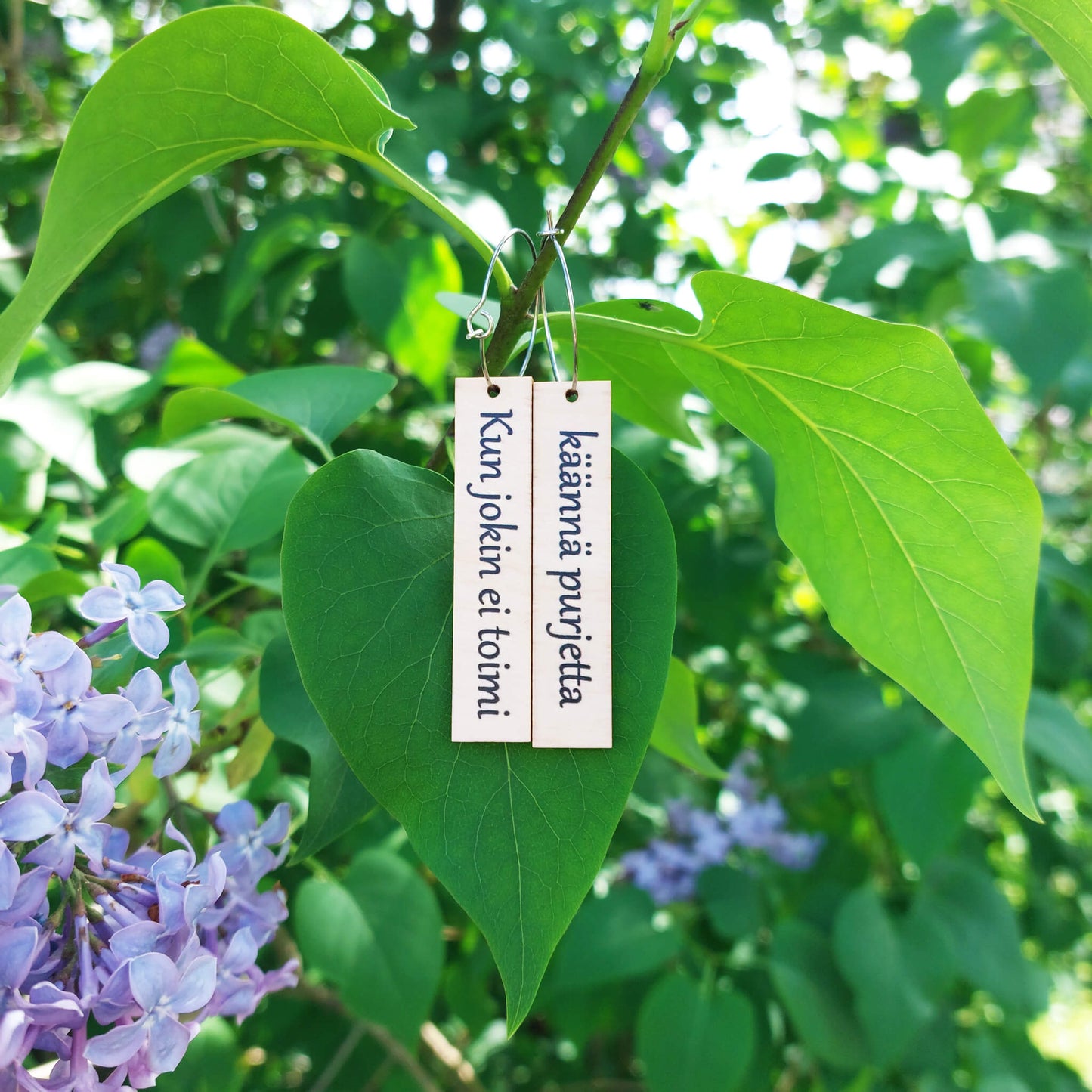 Puiset korvakorut tekstillä. Koruissa teksti "Kun jokin ei toimi käännä purjetta". Mietelause korvakorut.